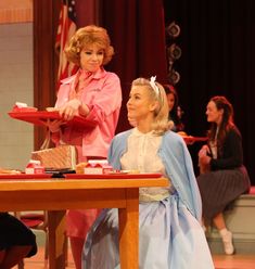 two women sitting at a table in front of a red tray with food on it