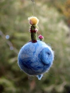 a blue ball with a small toy on it's side hanging from a wire