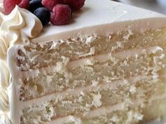 a close up of a slice of cake on a plate with raspberries and blueberries