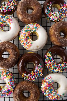 a bunch of doughnuts with sprinkles on a wire cooling rack