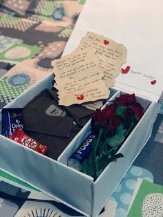 an open box with flowers, chocolates and notes in it sitting on a table