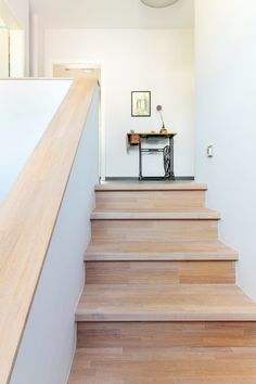 there is a sewing machine sitting on the top of some stairs in this room with white walls and wood flooring