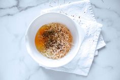 a white bowl filled with food on top of a table next to a napkin and fork