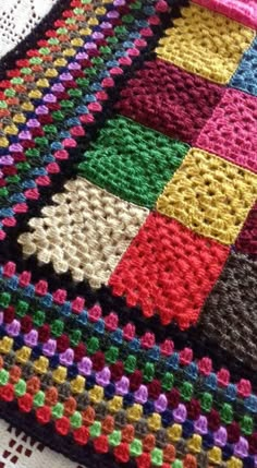 a crocheted blanket is laying on a tablecloth that has squares in it