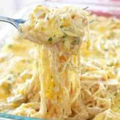 a spoon full of noodles and cheese being lifted from the casserole in a glass dish