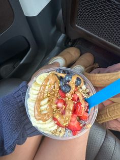 a person is holding a bowl of fruit and cereal in their hand while on the car seat