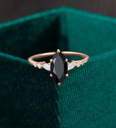 a black diamond ring sitting on top of a green velvet bag