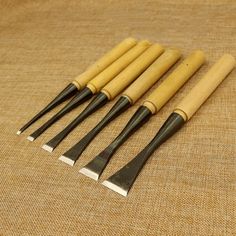 five wooden handled spats are lined up next to each other on a brown cloth