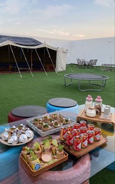 an outdoor picnic with food and drinks on the grass in front of a large tent