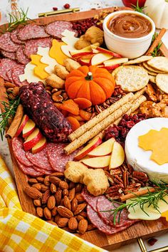 an assortment of meats, cheese and nuts on a wooden platter with a yellow checkered napkin