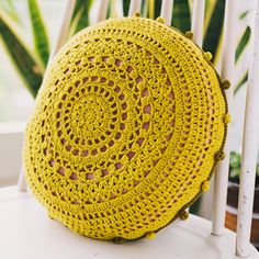 a yellow crocheted bag sitting on top of a white chair