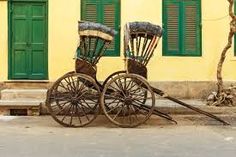 two old fashioned chairs sitting on the side of a road next to a building with green shutters