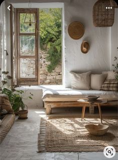 a living room filled with lots of furniture next to an open window and potted plants