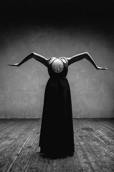 a woman in a long black dress is balancing herself on her back with one hand