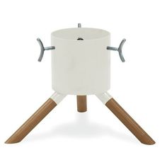 a white pot with wooden legs and two handles on an easel stand for serving food