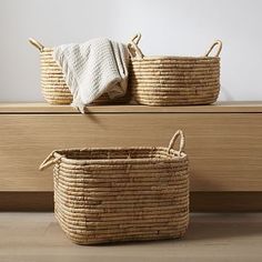 two woven baskets sitting on top of a wooden shelf