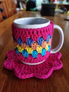 a crocheted coffee cup and saucer on a wooden table