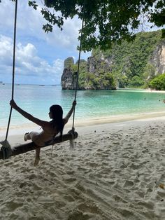 a woman sitting on a swing at the beach