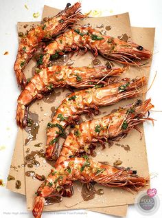 four pieces of cooked shrimp sitting on top of a piece of parchment paper with garnishes