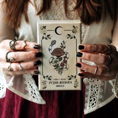 a woman holding a tarot card in her hands with the letter c on it