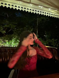 a woman in a red dress sitting at a table with her hand on her face