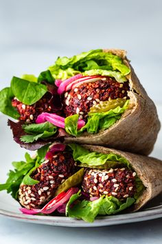 two wraps filled with lettuce, red onions and other vegetables on a plate