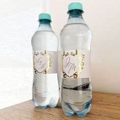 two water bottles with labels on them sitting on a wooden table next to each other