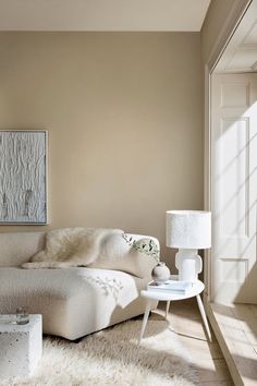 a white couch sitting on top of a wooden floor next to a table and lamp