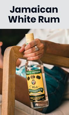 a bottle of jamaican white rum sitting on top of a wooden chair next to a person