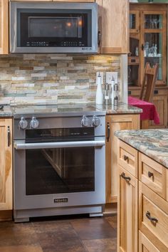 a stainless steel oven in a kitchen with wooden cabinets and granite counter tops on the floor