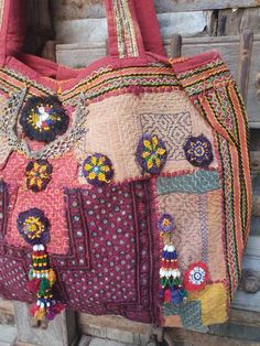 an old handbag is hanging on a wooden door with beads and tassels