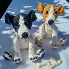 two crocheted dogs sitting next to each other with a bone in front of them