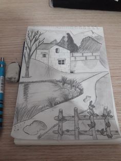 a pencil drawing of a farm scene on a notebook with a pen next to it