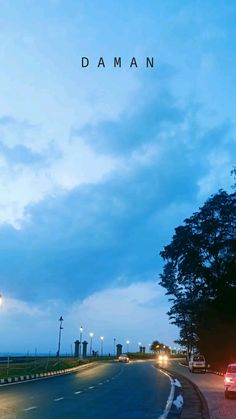 a car driving down the road at night with its lights on and dark clouds in the sky