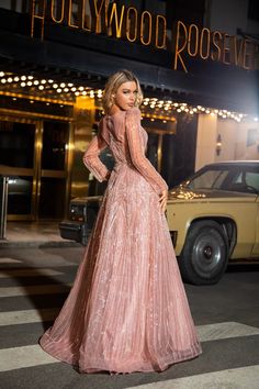 a woman standing in front of a hollywood roosevelt hotel at night with her hands on her hips