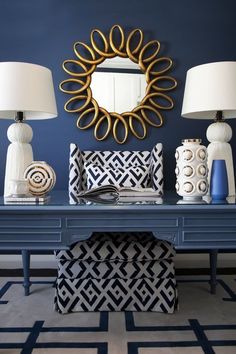 a blue table with two lamps and a mirror on it's wall above it