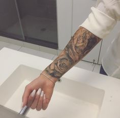 a person with a tattoo on their arm is holding a knife in front of a sink