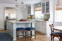 a kitchen with two blue stools in front of an island and counter top area