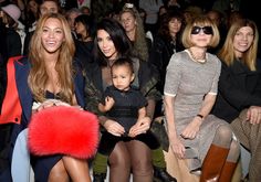 three women sitting next to each other in front of a crowd at a fashion show