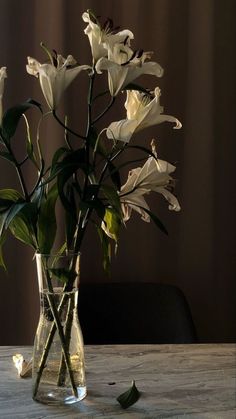 a vase filled with white flowers on top of a wooden table