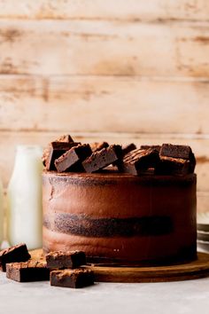 a chocolate cake sitting on top of a wooden table next to a bottle of milk