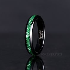 a wedding band with green glitter inlaying the center and black ceramic inside it