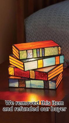 two stained glass books sitting on top of a wooden table next to a lamp that says, we removed this item and returned our buyer