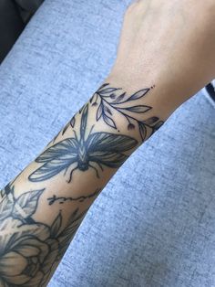 a person's arm with tattoos on it and flowers in the middle of their arm