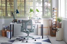 an office area with a desk, chair and bookshelf on the floor in front of two windows