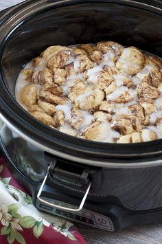 a crock pot filled with cinnamon rolls covered in icing