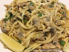 a plate of pasta with mushrooms and lemon wedges