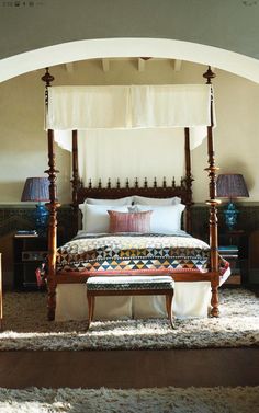 a canopy bed sitting in the middle of a bedroom next to two tables and lamps