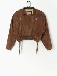 "Vintage cropped tan leather jacket with belt by Leather Sound. The jacket is genuine leather that is super soft to touch, has a cotton lining and is fastened at the front with a gold zip with a \"LS engraved\", a brown leather belt and drawstrings on the hem. The jacket also has three functional pockets with shiny gold zips and one non-functional pocket. Made in the UK from a heavyweight soft leather, with a cotton lining. Made circa 1980. Our recommended size: Small to medium Label Says: Small Fall Cropped Belted Jacket, Brown Leather Long Sleeve Cropped Jacket, Brown Leather Cropped Jacket With Long Sleeves, Spring Brown Belted Leather Jacket, Leather Jacket With Belt, Tan Leather Jacket, Tan Leather Jackets, Vintage Windbreaker, Cat Sweatshirt