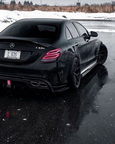 a black mercedes is parked in the snow